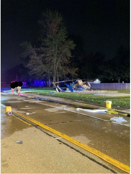 Photograph 2 – View of the helicopter and the tree it impacted at night, from the NTSB investigation of Messerschmitt-Bolkow-Blohm BK 117 accident near Hartford, Illinois, April 25, 2025