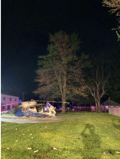 Photograph 3 – View of the helicopter and the tree it impacted at night, from the NTSB investigation of Messerschmitt-Bolkow-Blohm BK 117 accident near Hartford, Illinois, April 25, 2025