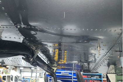 Photograph 7 – View of the substantial damage sustained to the rear right underside of the fuselage inside of a hangar, from the NTSB investigation of Bell Helicopter Textron Canada 505 accident near Fort Worth, Texas, August 27, 2025