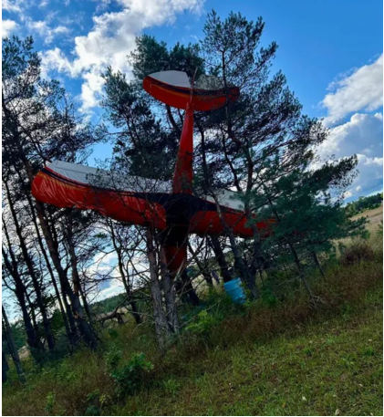 Photograph 1 – View of the top of the inverted airplane in trees, from the NTSB investigation of Amateur-built CCK-2000 accident near Thompsonville, Michigan, September 7, 2025