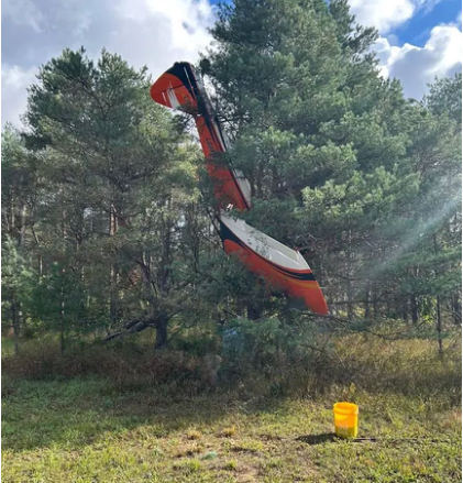 Photograph 2 – View of the left side of the inverted airplane in trees, from the NTSB investigation of Amateur-built CCK-2000 accident near Thompsonville, Michigan, September 7, 2025