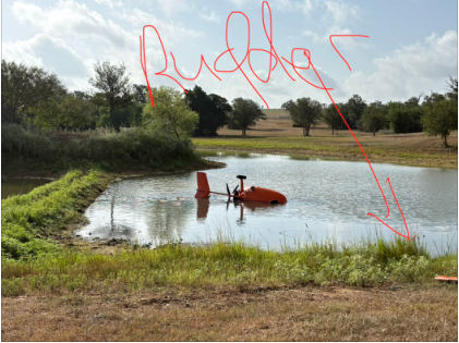 Photograph 3 – Accident site showing rudder on shoreline of pond, from the NTSB investigation of Rotor Effects LLC M24 PLUS accident near Waelder, Texas, August 15, 2026