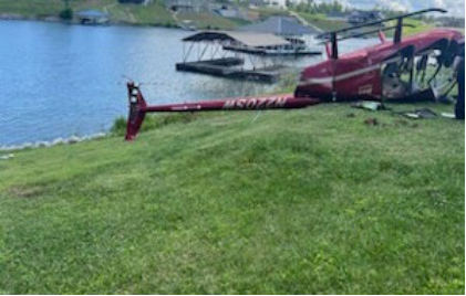 Photograph 1 – Inverted helicopter on private property, from the NTSB investigation of Robinson R44 accident near Gilbertsville, Kentucky, June 2, 2024