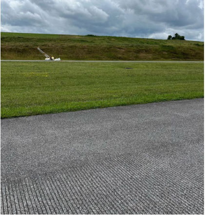 Photograph 5 - Postaccident view of wreckage from runway, from the NTSB investigation of Cessna A185F accident near Rural Retreat, Virginia, July 21, 2024