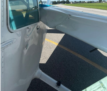 Photograph 3 – Postaccident view of low-wing’s wing broken through high-wing’s window, from the NTSB investigation of Cessna 172N and Piper PA-28-161 accident near Immokalee, Florida, July 28, 2024