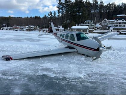 Photog rap h 2 –Front vie w of white airp lane with b lue and re d strip e s re sting on snowb ank (Courte sy of FAA), from the NTSB investigation of Beech A36 accident near Alton Bay, New Hampshire, February 23, 2025