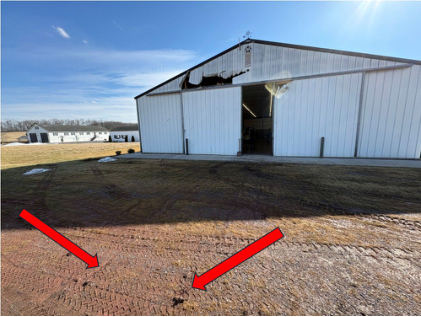 Photograph 3 – View of the Impacted Hangar and Area Where Helicopter was Located at Start of Liftoff. Arrows Point to Marks From Both Skids, from the NTSB investigation of Hughes 269A accident near Gettysburg, Pennsylvania, February 21, 2026
