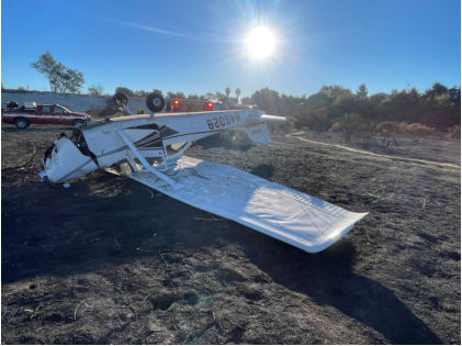 Photograph 1 – View of inverted airplane and substantial damage to the right wing lift strut, vertical stabilizer and rudder, from the NTSB investigation of Cessna 172I accident near Los Angeles, California, November 14, 2024