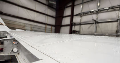 Photograph 2 – View of substantial damage in the form of deformation of left wing upper skins., from the NTSB investigation of Beech C90A accident near Helena, Montana, March 16, 2025