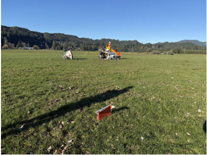 Photograph 1 – Helicopter wreckage in a grass field as viewed from the front., from the NTSB investigation of Bell 206L-3 accident near Logsden, Oregon, January 15, 2026